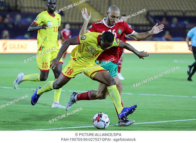 05 July 2019, Egypt, Cairo: Morocco's Nordin Amrabat (R) and Benin's Mama Seibou battle for the ball during the 2019 Africa Cup of Nations round of 16 soccer...