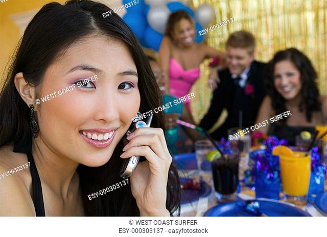 Well-dressed teenager girl using cell phone at school dance