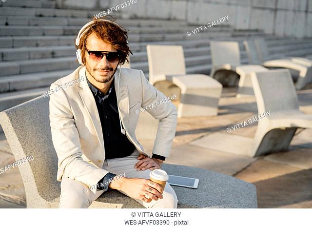 Portrait of businessman wearing sunglasses listening music with headphones