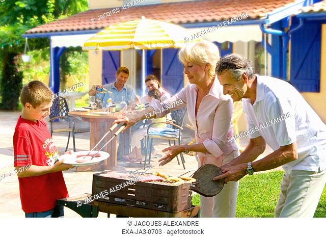 Multi-generational family barbecuing on patio