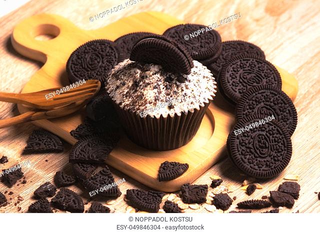 Chocolate cupcake and cookies are on wooden plate