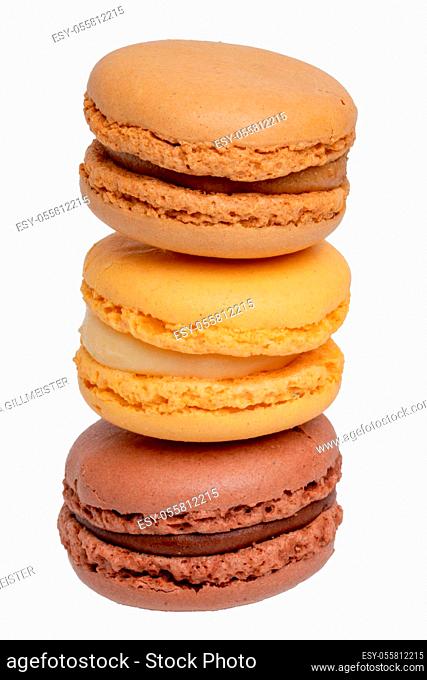 Pastries, desserts and sweets. Close-up of a yellow french vanilla macaroon, a yellow lemon macaroon and a brown chocolate macaroon isolated on a white...