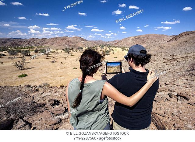 Couple taking picture with tablet in Damaraland - Huab Under Canvas, Damaraland, Namibia, Africa