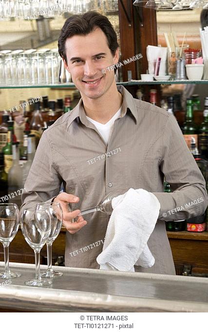 Male bartender drying wine glasses