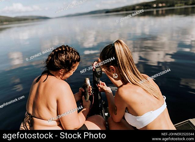 Women on boat taking photo of fish