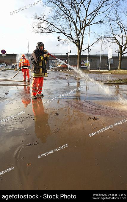 09 February 2021, Rhineland-Palatinate, Vallendar: Employees of the municipal building yard clean the Bundesstraße 42 from the mud that remained there after the...