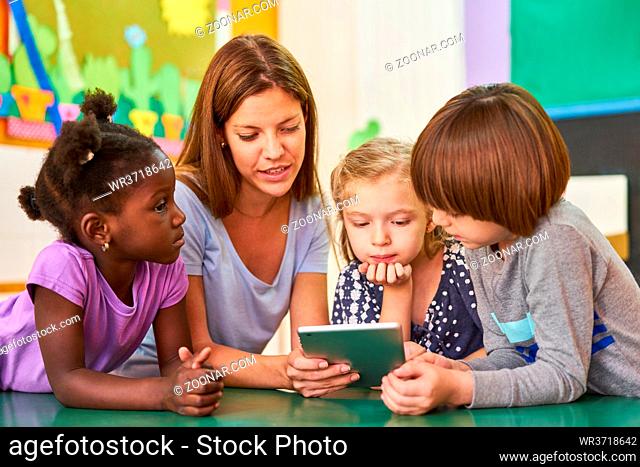 Kinder und Erzieherin beim Vorlesen aus einem Ebook oder lernen am Tablet Computer