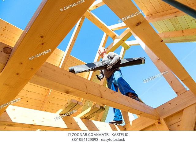 Carpenter roofer at work with wooden roof construction