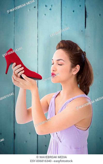 Composite image of elegant brunette kissing a shoe