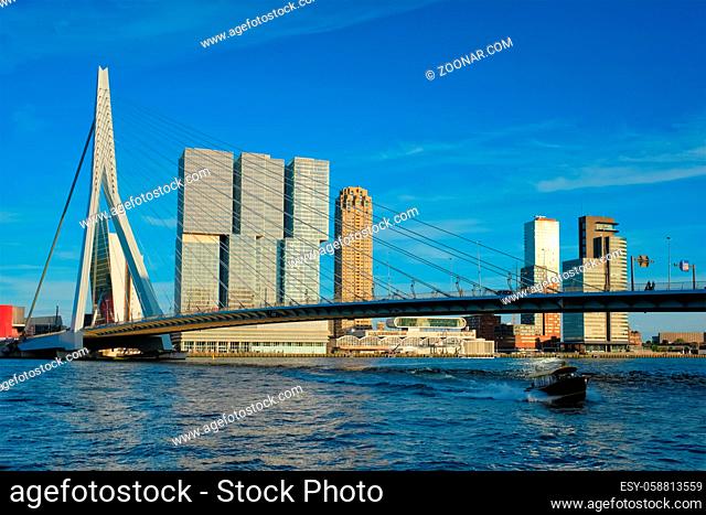 Erasmus bridge over Nieuwe Maas river on sunset with speed boat passing under the bridge. Rotterdam, Netherlands