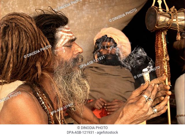 Naga sadhus from the Juna Akadha sits with his Trishul at their camp during the Ardh Kumbh Mela , , , India
