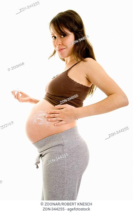 Junge schwangere Frau cremt ihren Babybauch ein