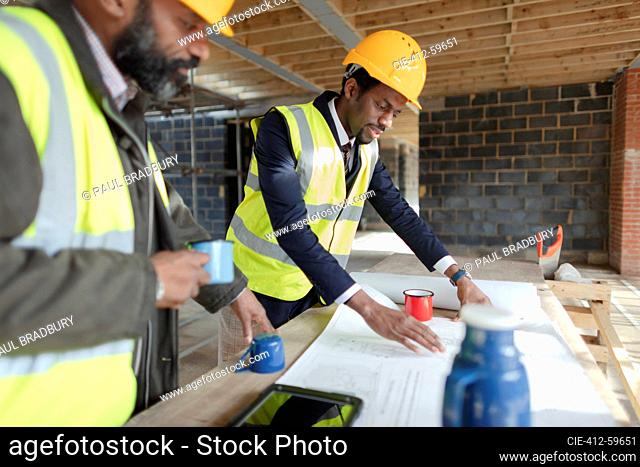 Engineer and architect reviewing blueprints at construction site