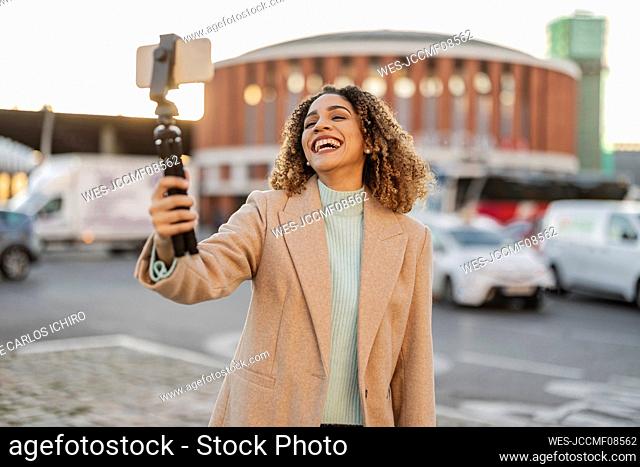 Happy woman filming through mobile phone on tripod