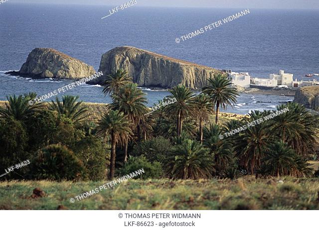 La Isleta Peninsula with rocks and white cubic houses being situated behind palm trees in the Mediterranean Sea, Natural Park Cabo de Gata-Nijar
