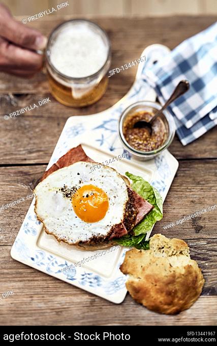 fried egg and ham sandwich served with sweet mustard and beer