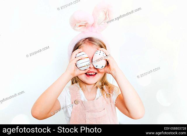 Little girl with Easter eggs and bunny ears hat. High quality photo