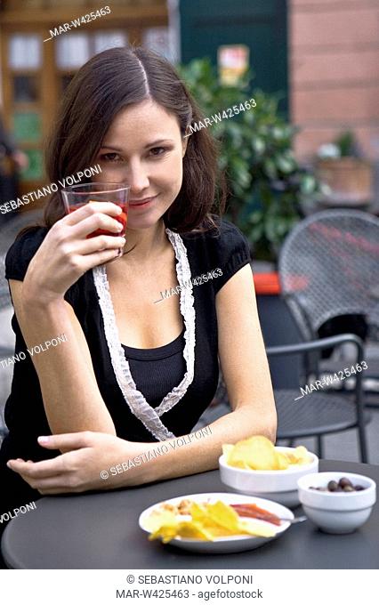 ragazza beve un aperitivo seduta al tavolo di un bar