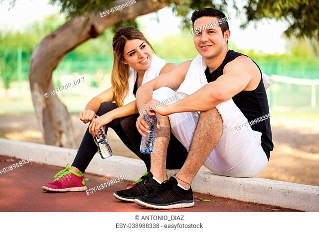 Attractive young couple taking a break from exercising and drinking some water together