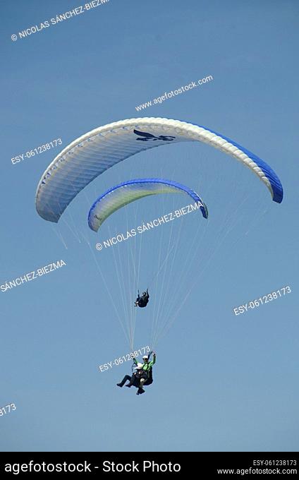 Two paragliders flying in a blue sky
