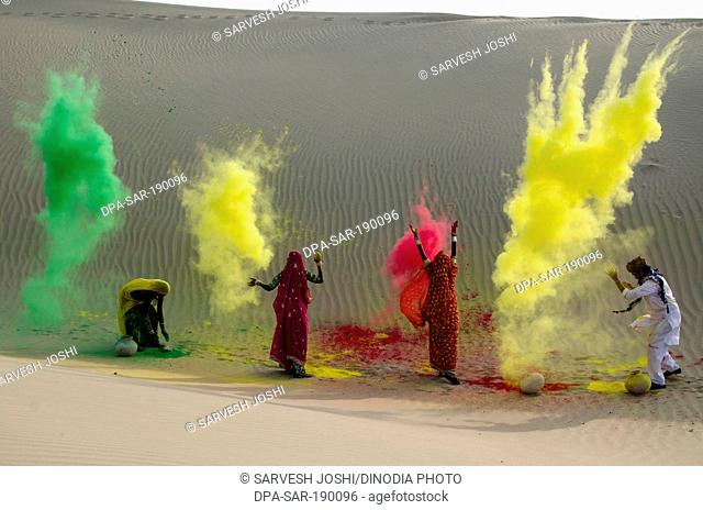 Men and women throwing dry colour in holi festival Jaisalmer Rajasthan India Asia NO MR