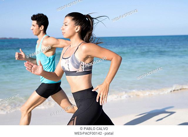 Spain, Canary Islands, Fuerteventura, young couple running on the beach