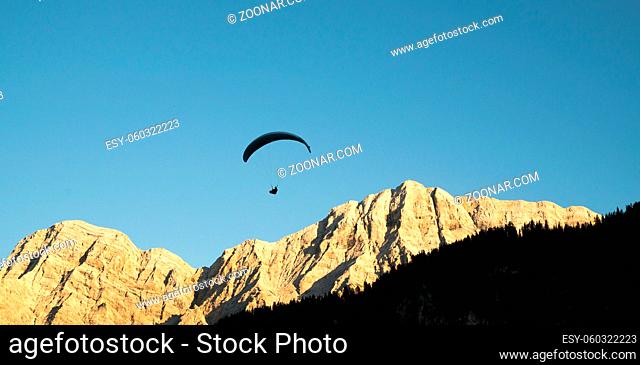 silhouette of paraglider in Dolomite mountain landscape in evening light near La Valle
