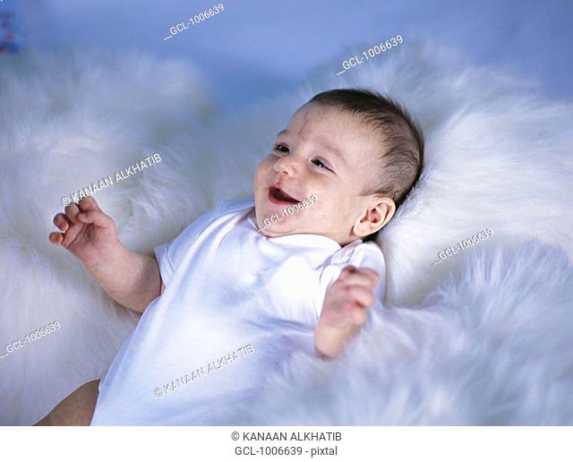 Infant lying on a white fluffy blanket