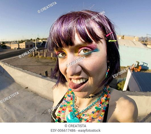 Fisheye shot of young woman sticking out her tongue on a roof