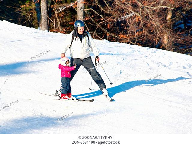 BUKOVEL, UKRAINE - DEC 11, 2015: Father with a child on a ski slope in Bukovel. Bukovel is the most popular ski resort in Ukraine