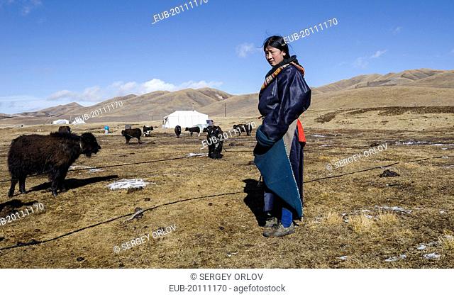 Young woman from a Tibetan nomad family on a highland pasture near family tent