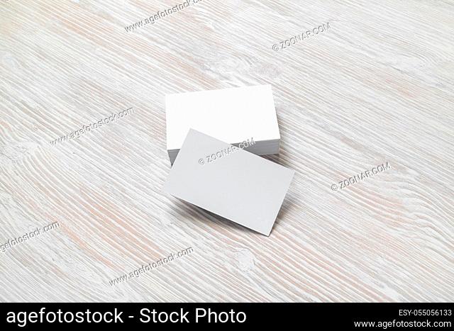 Photo of blank business cards with soft shadows on light wood table background. Mock-up for branding identity