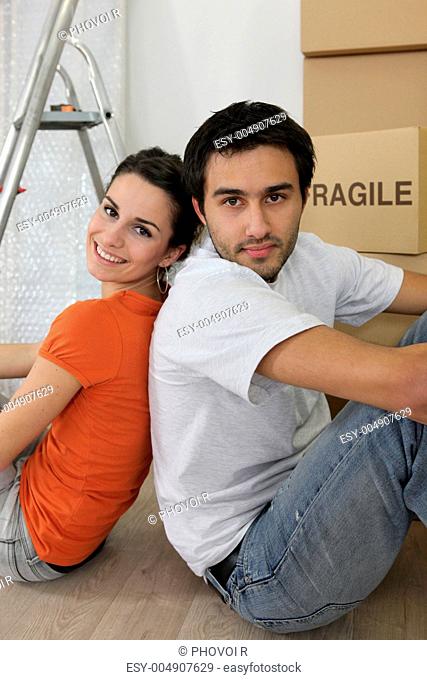 Couple sat by ladder and boxes