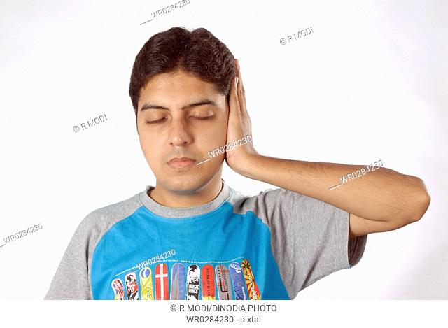 South Asian Indian man doing exercise closing eyes keeping left hand to close left ear MR628