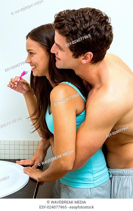 Couple hugging while brushing teeth