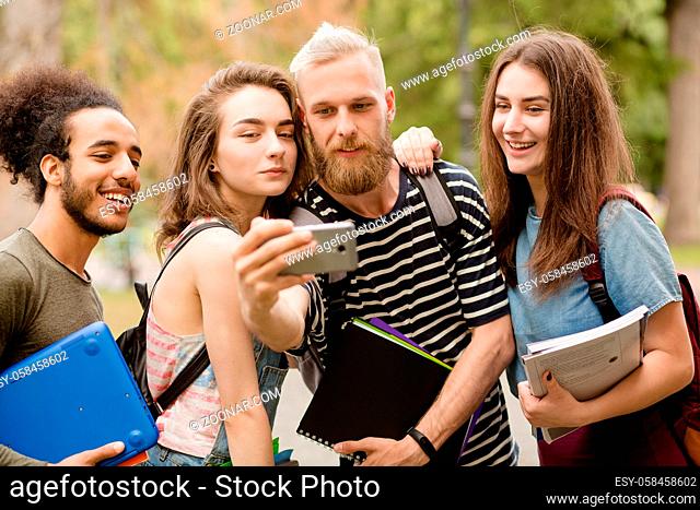 Four students making selfie shots. Beautiful young people smiling, making selfie on phone camera