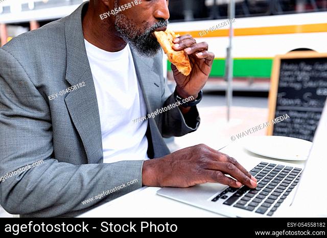 African American man working on his laptop at coffee terrace