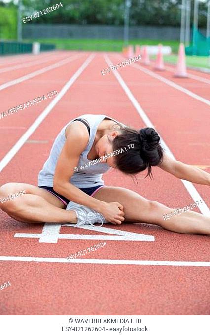 Woman stretching her leg on a track