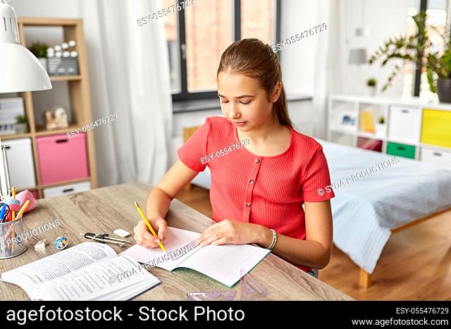 student girl with ruler drawing line in notebook