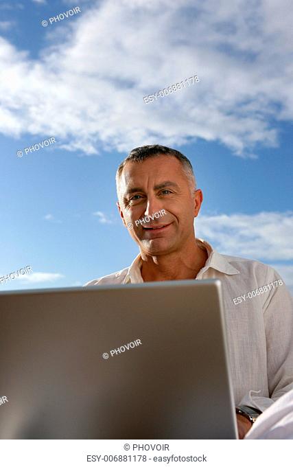 mature man working outdoors with laptop