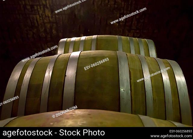 wine barrels from hard wood strapped with steel hoops stacked in a dark cellar winery