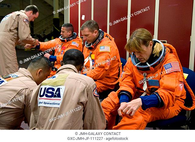 Astronauts Kathryn Hire, STS-130 mission specialist; Terry Virts Jr. (center), pilot; and George Zamka, commander, don training versions of their shuttle launch...