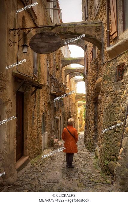 A tourist observes the architecture of a street of Bussana Vecchia, Sanremo, Province of Imperia, Liguria, Italy, Europe