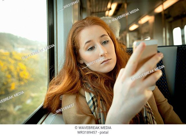 Woman using mobile phone while travelling in train