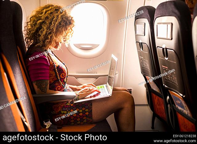 Woman travel on airplane and work with computer laptop and wireless internet connection on beard - people and flight airport activity - modern digital nomad and...