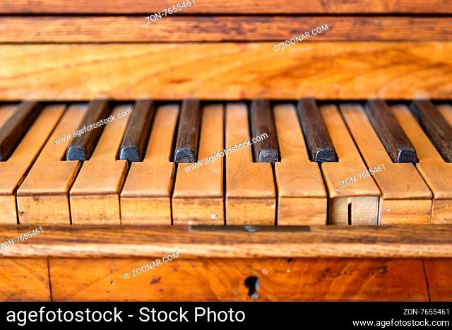 Close up front view of old wooden piano wtih brown and black keys