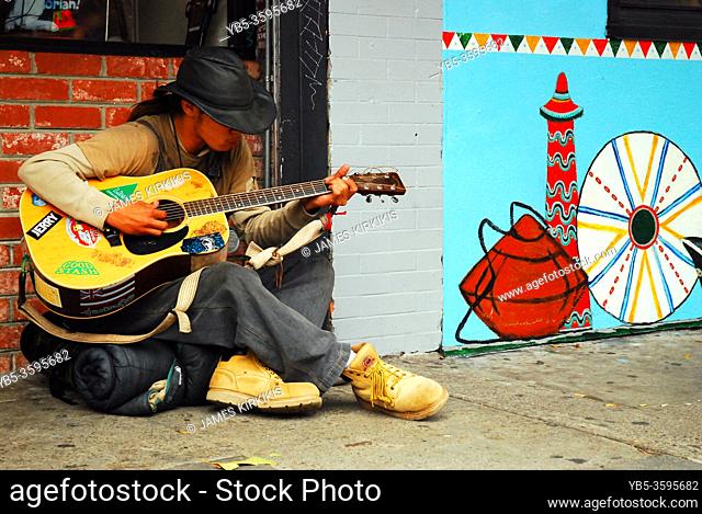 A young man plays his guitar on the streets of Haight Ashbury district in San Francisco