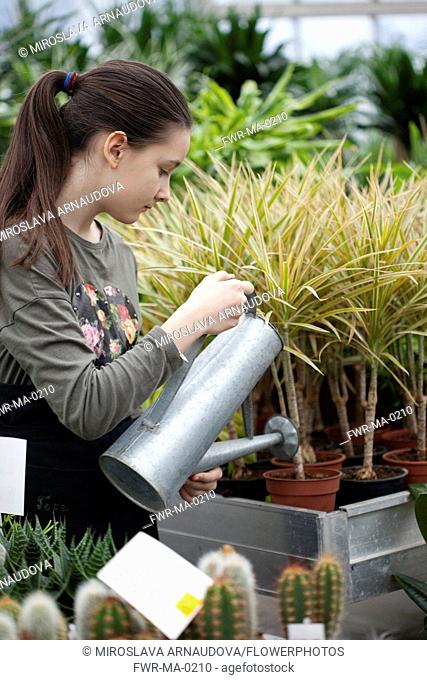 Young girl working in garden centre, Watering plants