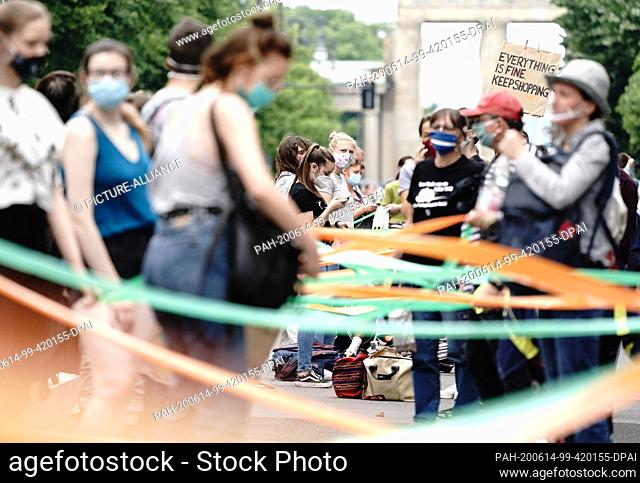 14 June 2020, Berlin: Participants of the demonstration of the alliance ""Indivisible"" against social injustice and racism stand with mouthguards and a rainbow...
