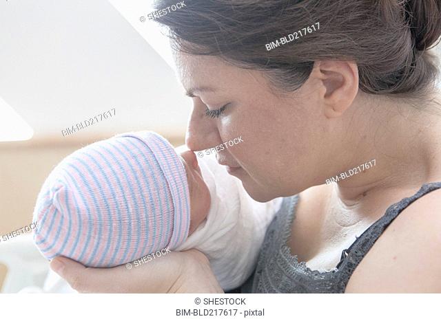 Caucasian mother rubbing noses with newborn daughter